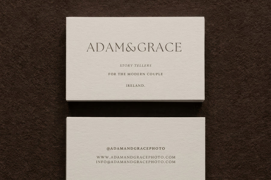 Adam and Grace business cards stacked on a brown surface