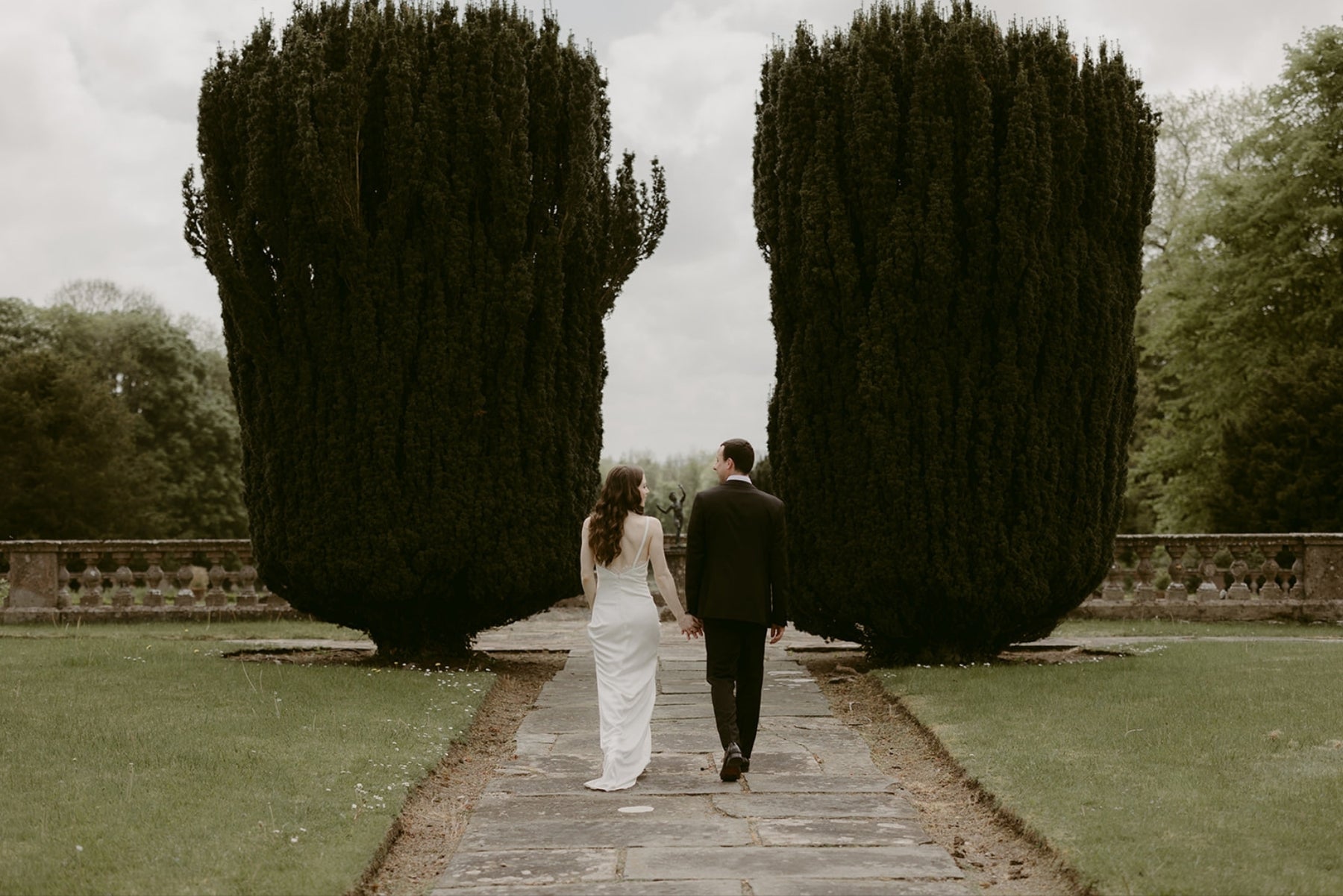 Bride and groom walking through a garden, wedding photography example