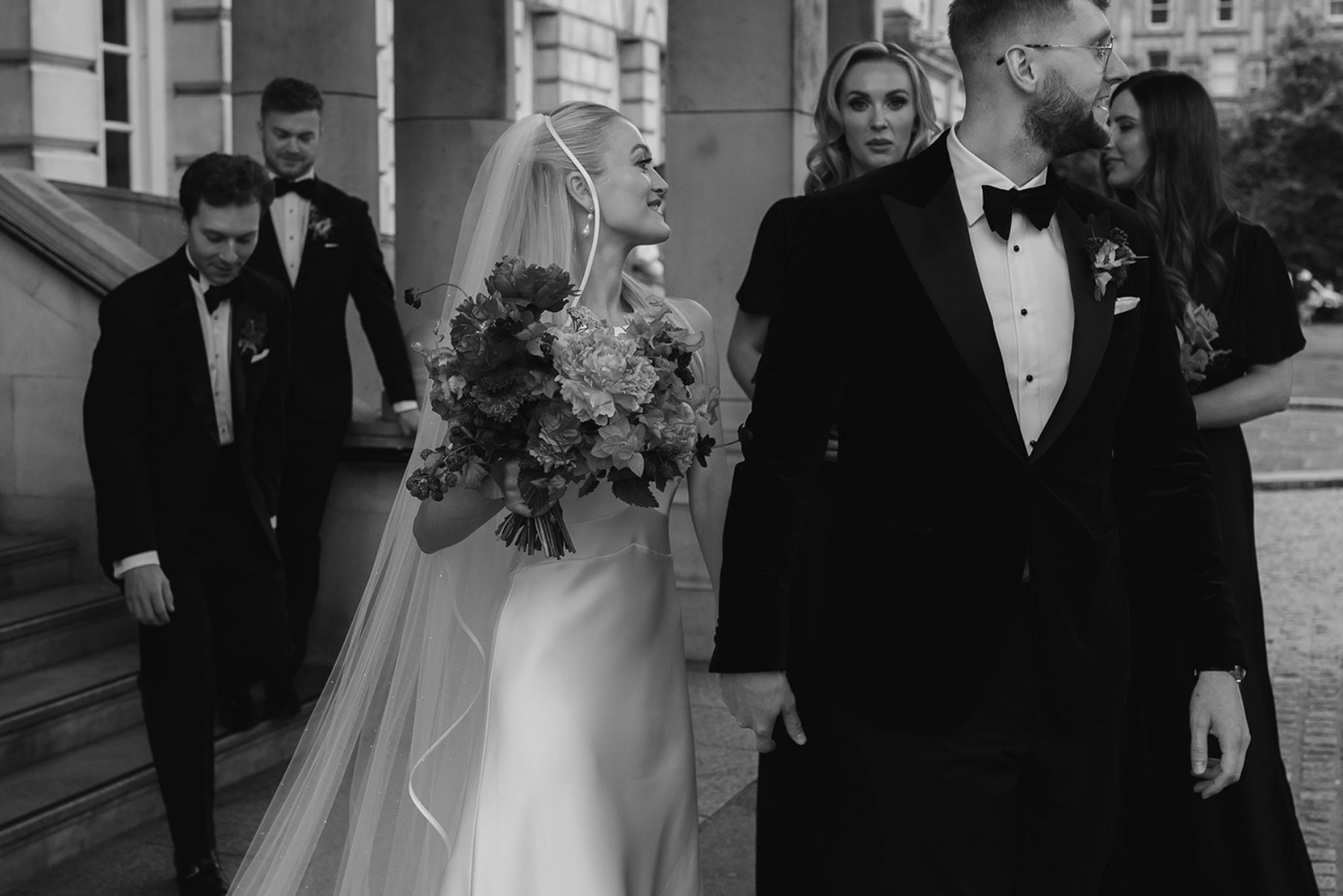 Black and white wedding couple walking with a bouquet