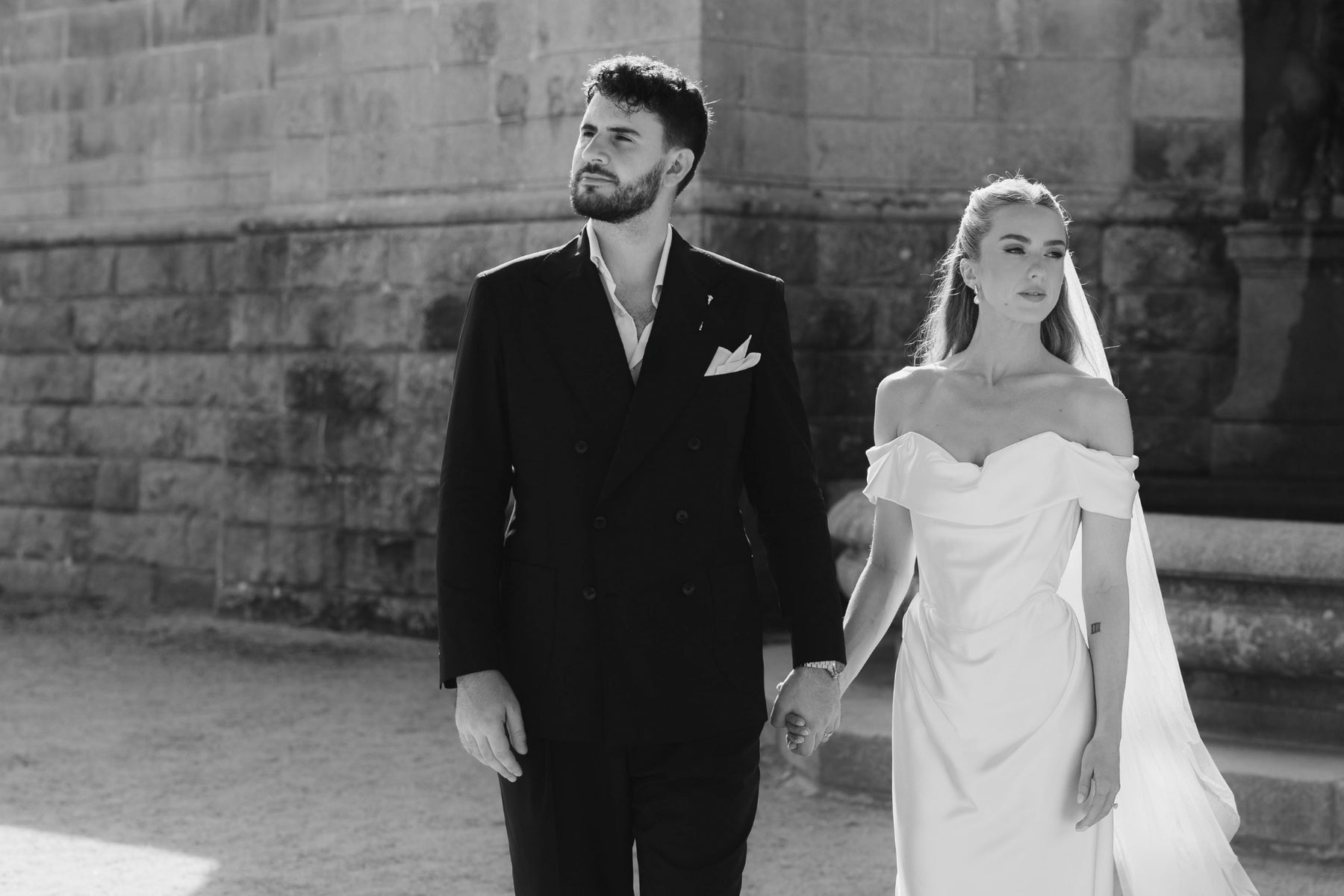 Bride and groom by a stone wall, natural wedding posing example